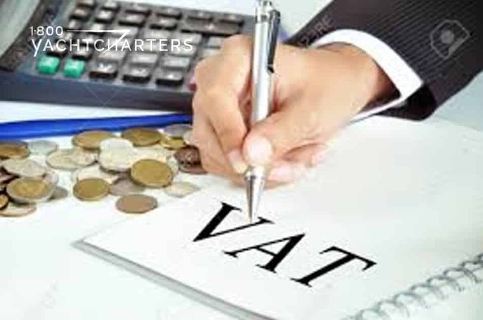 Photograph of a businessman writing on a piece of paper that says VAT. There are coins next to the piece of paper, and a computer keyboard beside it.