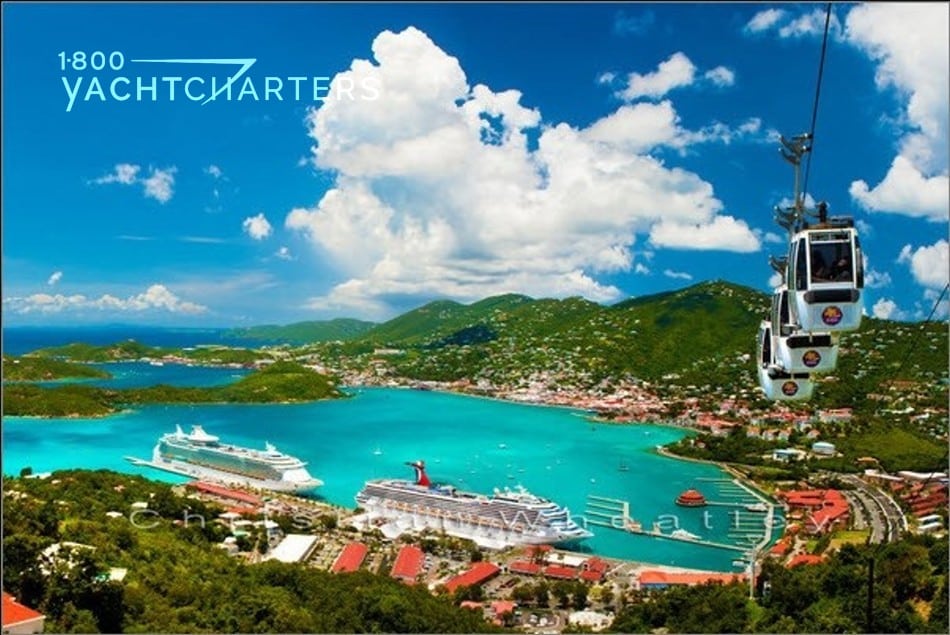 Aerial photograph of Charlotte Amalie Harbour in St. Thomas. There are cable cars coming down from the mountaintop.  There are boats in the marina and cruiseships docksed