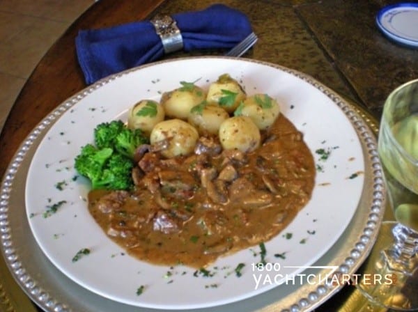 a white plate with veal zurich and white potatoes and broccoli on it