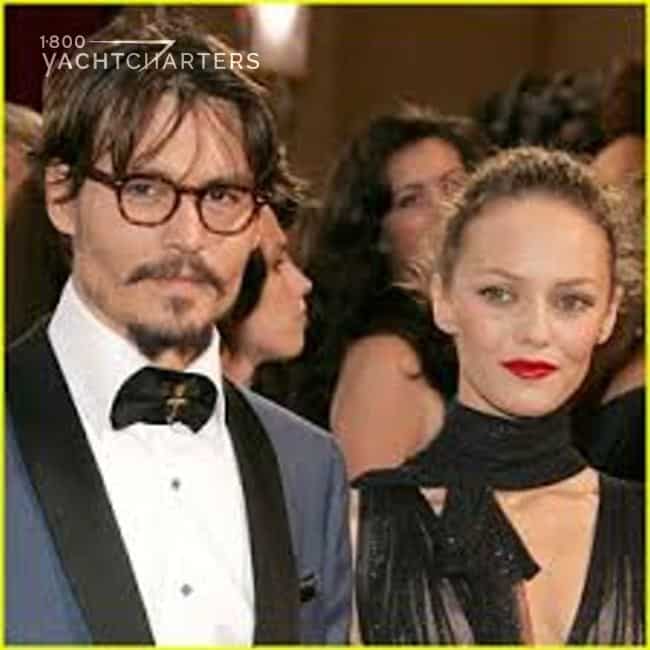 Photograph of Johnny Depp and Vanessa Paradis at a formal event. He is in a tuxedo. She is wearing a black dress and neck scarf. The photograph of of them from the chest up. They are looking at the camera.