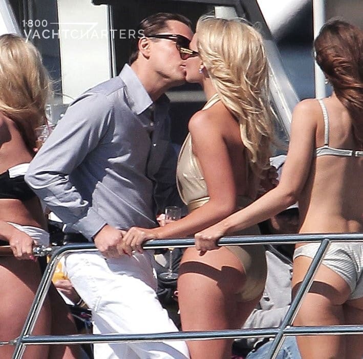 Photo of Leonardo DiCaprio on the deck of a yacht, surrounded by girls in bikinis. He is kissing a blond in a gold bikini.