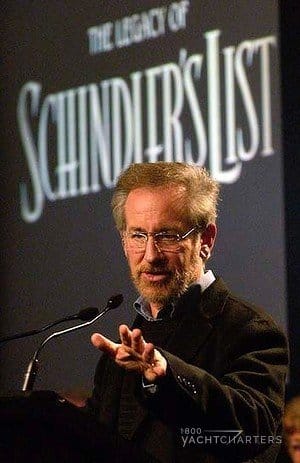 steven spielberg standing behind a podium in front of Schindler's List writing on wall