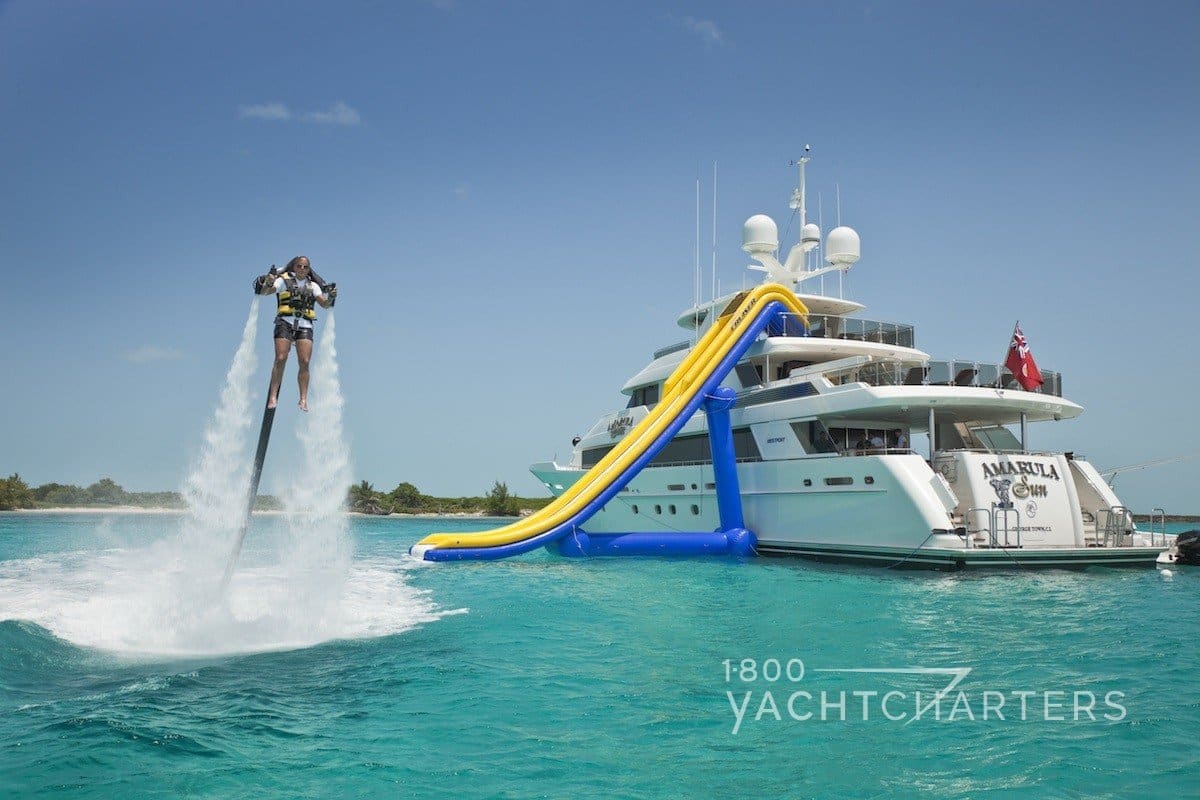 Back of yacht with inflatable slide set up and person flying over the water with a backpack like James Bond wore in the movie Thunderball