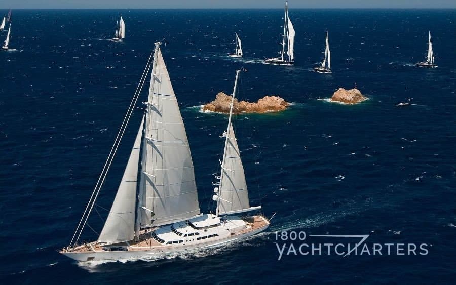 multiple sailboats sailing in a race with a large Perini Navi sailboat in the foreground