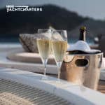 champagne in ice bucket next to full champagne flutes next to the ondeck jacuzzi of a yacht