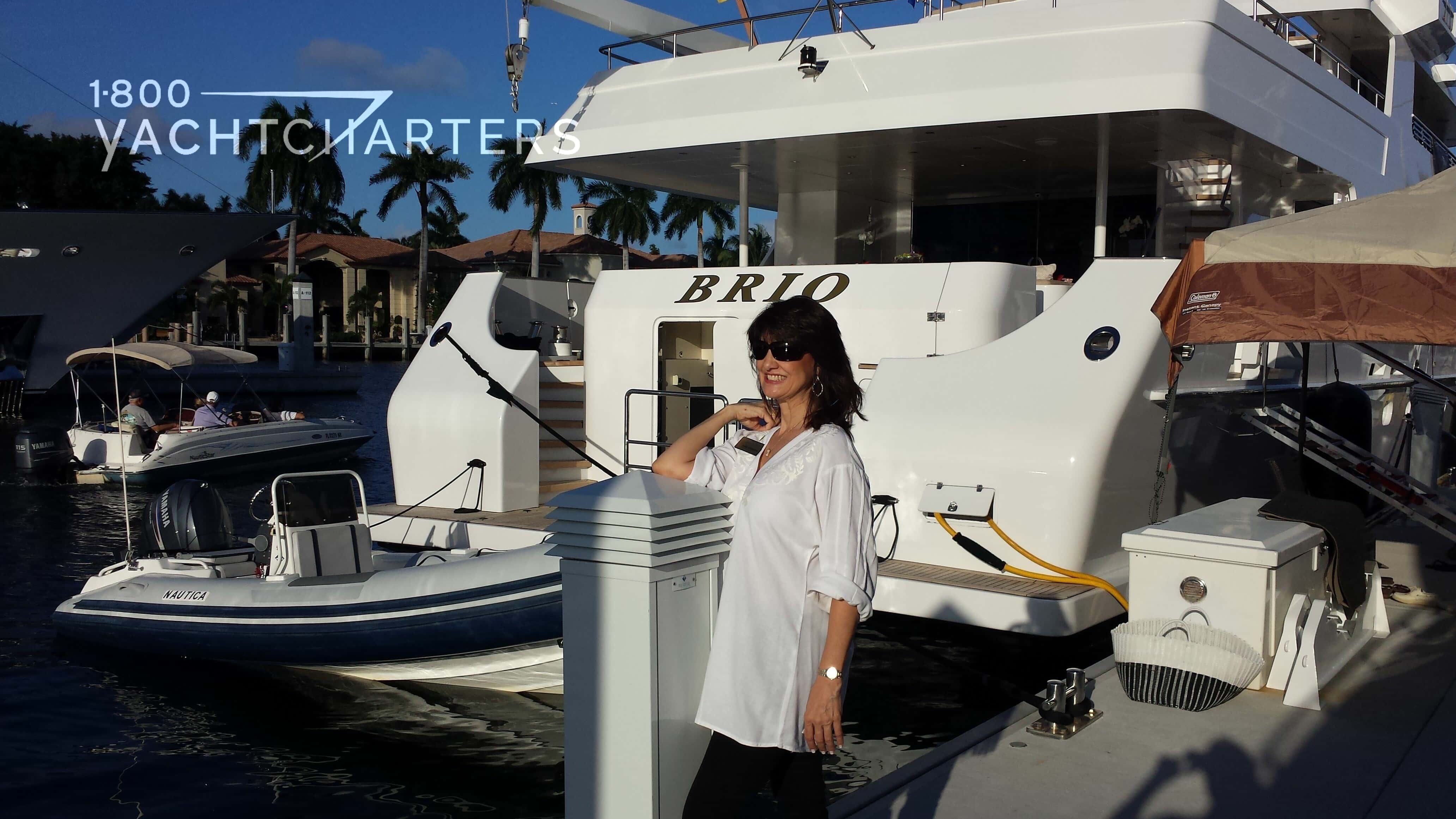 Photograph of Jana Sheeder on the dock at a superyacht show. She is looking toward the left side of the photograph. There is a large white yacht behind her.