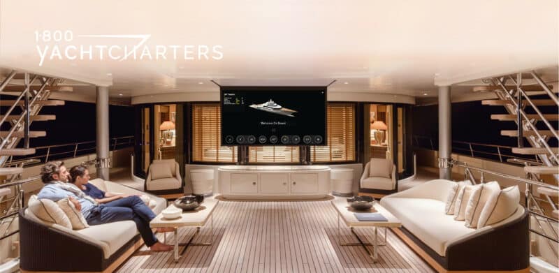 Photograph of a couple viewing a television screen in the main salon of a superyacht